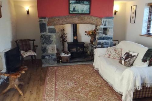 a living room with a white couch and a stone fireplace at Farm accommodation - The Lizard Peninsula, Cornwall in Helston