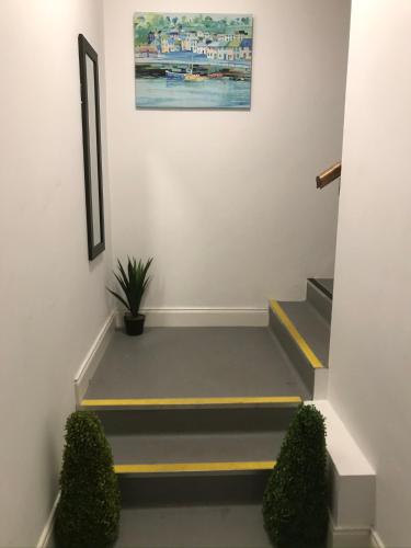 a hallway with stairs with a painting on the wall at Pier House Luxury Apartment in Dingle