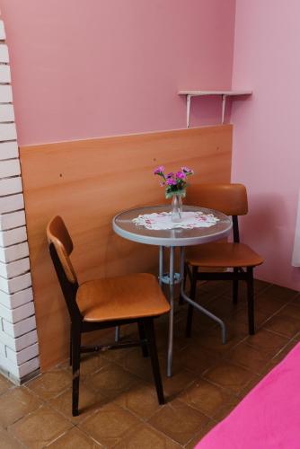 a table with two chairs and a vase of flowers on it at Vila Verona Sobe in Palić