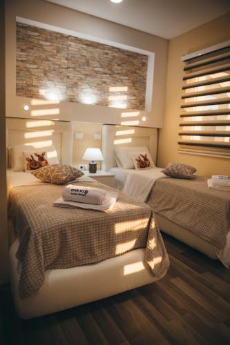 a bedroom with two beds and a brick wall at Adria centar Koćuša in Ljubuški