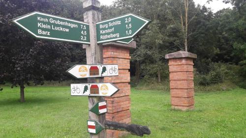un poste con señales de la calle en un campo en Ferienwohnung Am Skulpturenweg, en Hohen Demzin