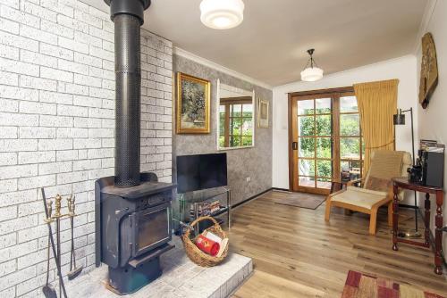a living room with a brick wall and a wood stove at Bidwell Cottage in Daylesford