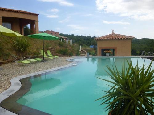 une grande piscine bleue avec un parasol dans l'établissement Villa Le Tournesol ADULT à partir de 16 ans, à Saint-Jean-de-la-Blaquière