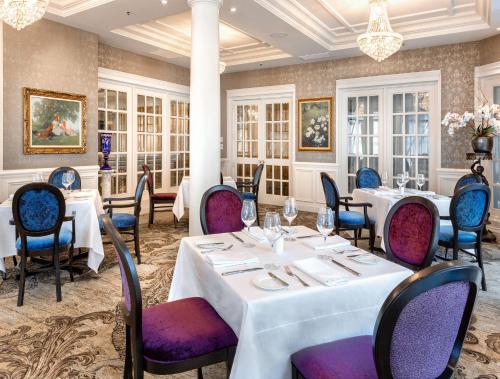 a restaurant with white tables and purple chairs at Chateau Vaudreuil in Vaudreuil-Dorion