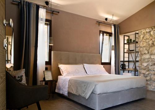 a bedroom with a bed and a chair and windows at Oikos in Terre di Zaccanello in Racalmuto