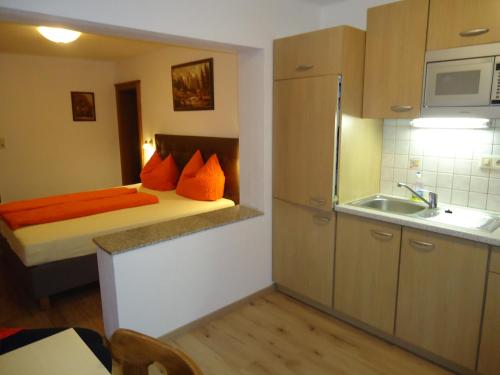 Mały pokój z łóżkiem z pomarańczowymi poduszkami w obiekcie Gästehaus Birkenheim w mieście Zell am Ziller