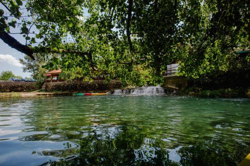 a pond with a waterfall in front of a tree at Adria centar Koćuša in Ljubuški