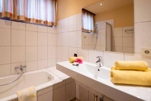 La salle de bains est pourvue d'un lavabo, d'une baignoire et d'un miroir. dans l'établissement All Suite Hotel Garni Leithner, à Pertisau