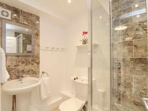 a bathroom with a toilet and a sink and a shower at The Old Post Office in Helston