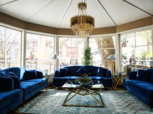 a living room with blue couches and a chandelier at Hotell Arkad in Västerås