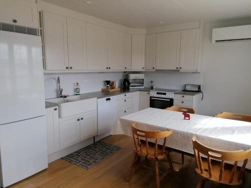 a kitchen with white cabinets and a table with chairs at Dimgården in Leksand