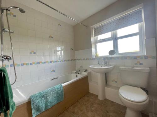 een badkamer met een bad, een wastafel en een toilet bij Derrybrook Cottage, Twin or Superking, Seven Springs Cottages in Cheltenham