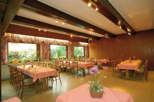 a dining room with tables and chairs with pink tablecloths at Hotel Weinhaus Kreuter in Koblenz