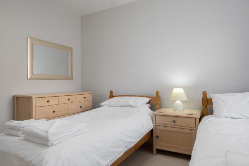 a bedroom with two beds and a dresser and a mirror at Stonehaven ground floor home with a spectacular harbour view. in Stonehaven