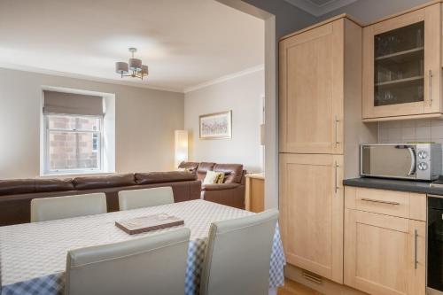a kitchen and living room with a table and a microwave at Stonehaven ground floor home with a spectacular harbour view. in Stonehaven