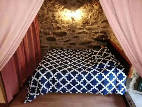 a bed with a blue and white comforter in a room at Molino de Louzao in Palas de Rei