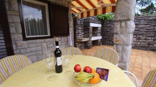 een tafel met een fles wijn en een schaal fruit bij Vacation house Dora in Malinska