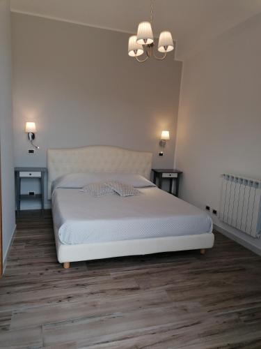 a bedroom with a white bed and a chandelier at Hotel Antica Cascina Del Golfo in Scopello