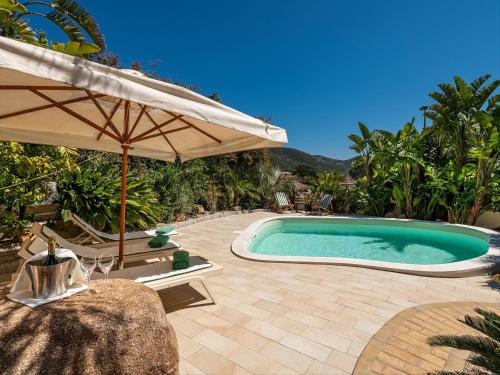 een zwembad met een parasol en een tafel en stoelen bij Giglio di Chia - Your Dream Holiday in Domus de Maria