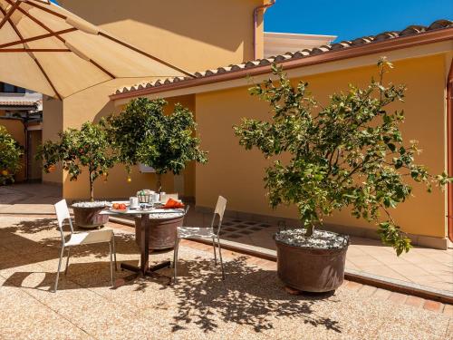 a patio with a table and chairs and trees at B&B Giglio di Chia in Domus de Maria