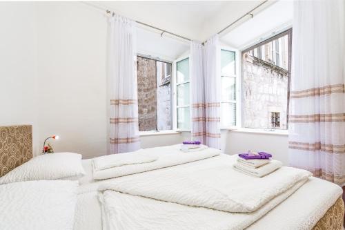 two beds in a white room with windows at Old Town Finest in Dubrovnik