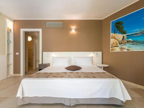 a bedroom with a white bed and a painting on the wall at B&B Giglio di Chia in Domus de Maria