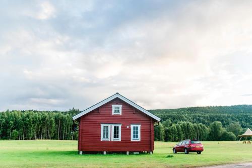 a red house and a car in a field at Alevi Camping in Stöllet