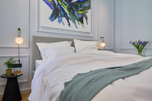 a bedroom with a white bed with a painting on the wall at Bota Palace in Dubrovnik