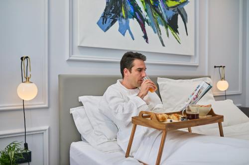 a man laying in bed eating food on a table at Bota Palace in Dubrovnik