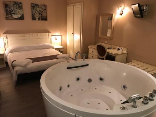 a bathroom with a large bath tub and a bed at Logis Hôtel restaurant Les Minotiers in Mirepoix