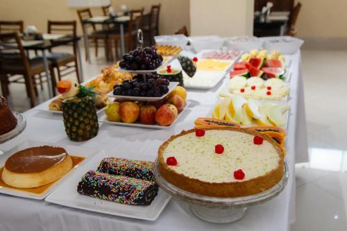 a table filled with different types of cakes and desserts at Capri Hotel in Duque de Caxias