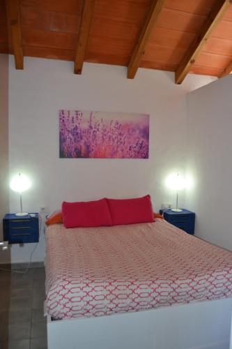 サオラにあるCasa-Estudio Pachamamaのベッドルーム1室(赤い枕とランプ2つ付)