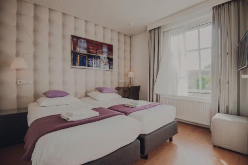 a bedroom with two beds and a large window at Herberg Sint Petrus in Hilvarenbeek