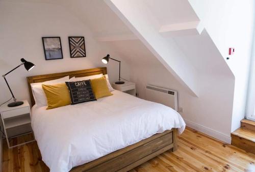 Schlafzimmer mit einem Bett mit weißer Bettwäsche und gelben Kissen in der Unterkunft Apartments in Dingle Town Center in Dingle