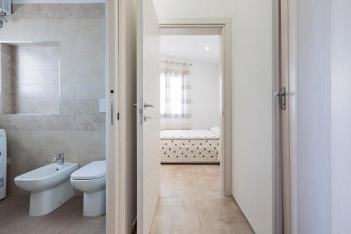 a white bathroom with a toilet and a sink at Villino Vanessa by BarbarHouse in Torre Lapillo