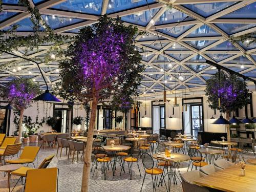 a restaurant with tables and chairs and purple flowers at Pestana Collection Plaza Mayor in Madrid