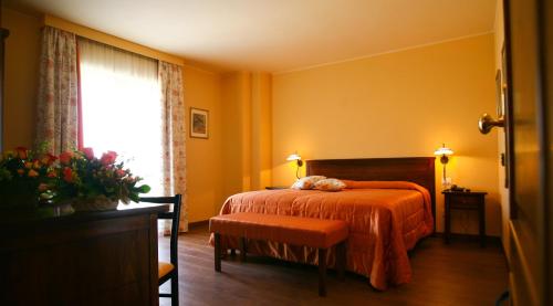 a bedroom with a bed with an orange blanket and a window at Hotel Ristorante Al Duca in Atessa