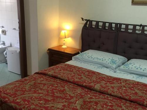 1 dormitorio con 1 cama con edredón rojo y lámpara en AGRITURISMO I LAMOI, en Finale Ligure