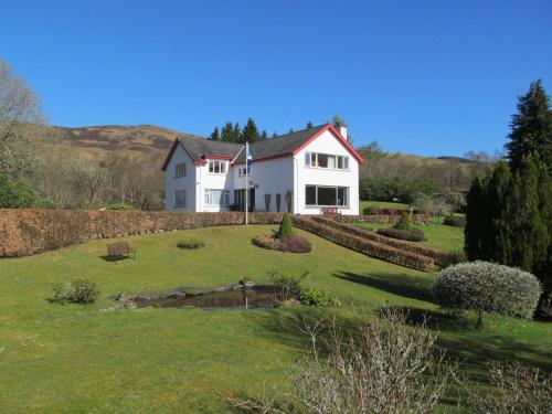 a white house on a hill with a yard at Torbeag House in Fort William