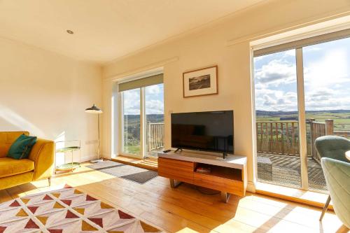 a living room with a television and large windows at Host & Stay - Strathview in Hexham