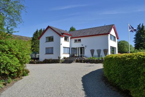 a white house with a flag on top of it at Torbeag House in Fort William
