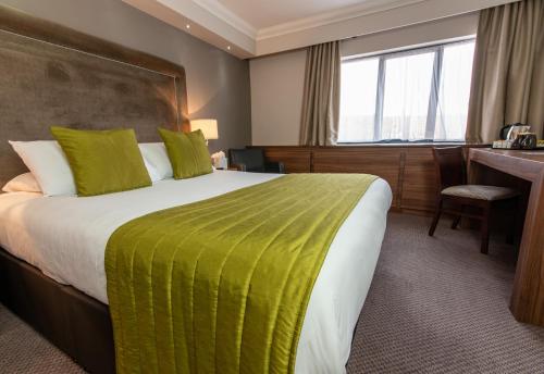 a hotel room with a large bed and a desk at Dukes Head Hotel Kings Lynn in Kings Lynn