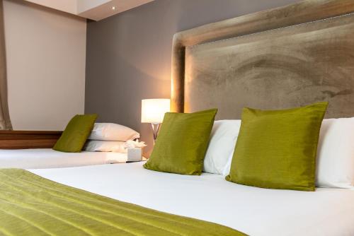 a hotel room with two beds with green pillows at Dukes Head Hotel Kings Lynn in Kings Lynn