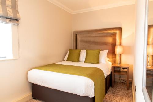 a bedroom with a large bed with green pillows at Dukes Head Hotel Kings Lynn in Kings Lynn