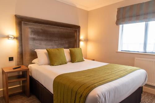 a bedroom with a large bed with a large headboard at Dukes Head Hotel Kings Lynn in Kings Lynn