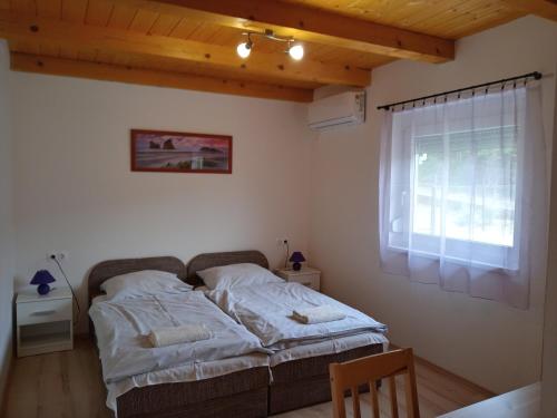 a bedroom with a bed in a room with a window at Napsugár Vendégház in Újudvar