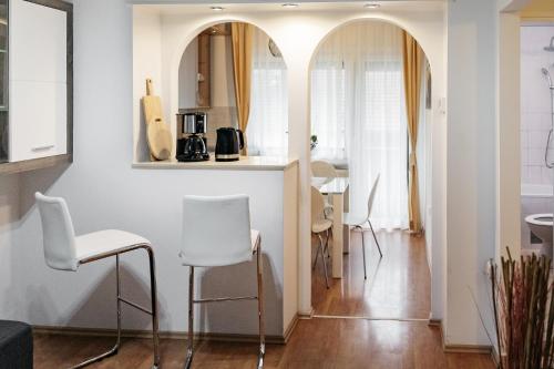 Il comprend un salon avec des chaises blanches et une cuisine. dans l'établissement Apartments Šentvid, à Ljubljana
