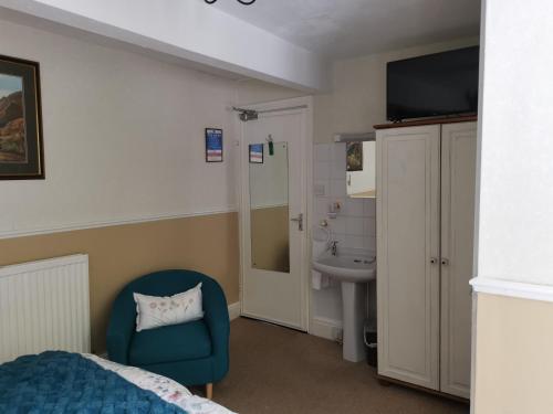 1 dormitorio con cama, silla y lavamanos en Brooklands Guest House, en Bowness-on-Windermere