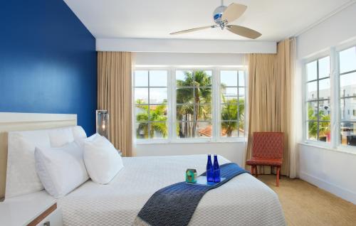 a bedroom with a white bed with a blue wall at Blue Moon Hotel in Miami Beach