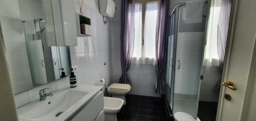 Baño blanco con lavabo y aseo en Appartamento in Piazza Italia, en SantʼAntìoco